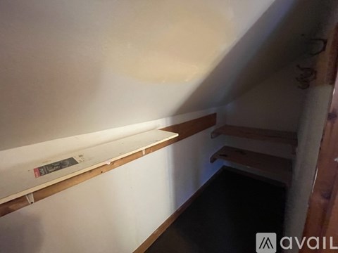A room with a white wall and a wooden shelf.