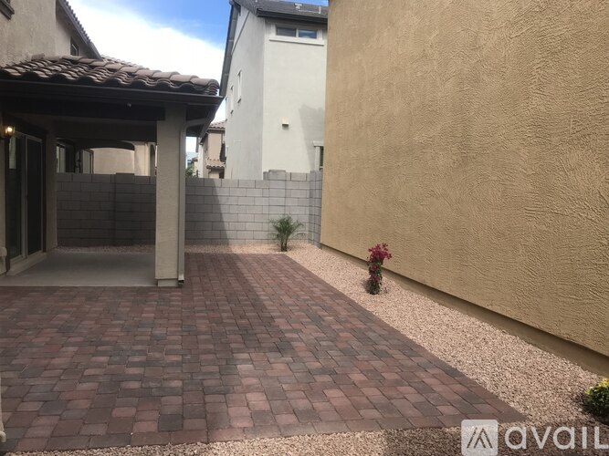 A patio with a brick pattern is surrounded by a wall and a building.
