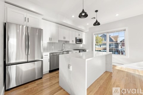 A modern kitchen with a refrigerator, cabinets, and a microwave.