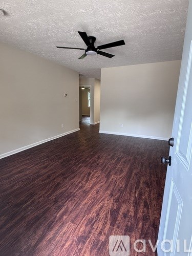 A room with a ceiling fan and wooden flooring.
