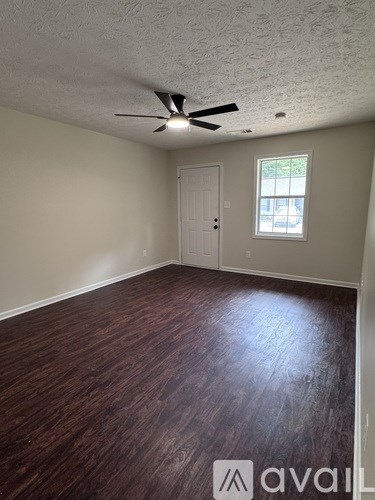 A room with a ceiling fan and wood flooring.