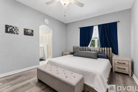 A bedroom with a bed, nightstand, and a fan.