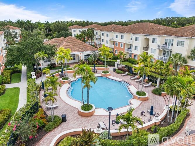A swimming pool surrounded by palm trees and apartment buildings.