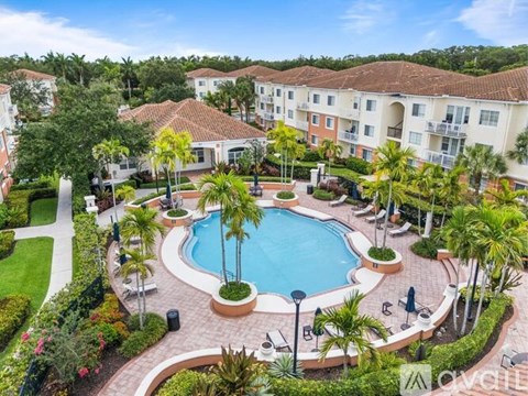 A swimming pool surrounded by palm trees and apartment buildings.