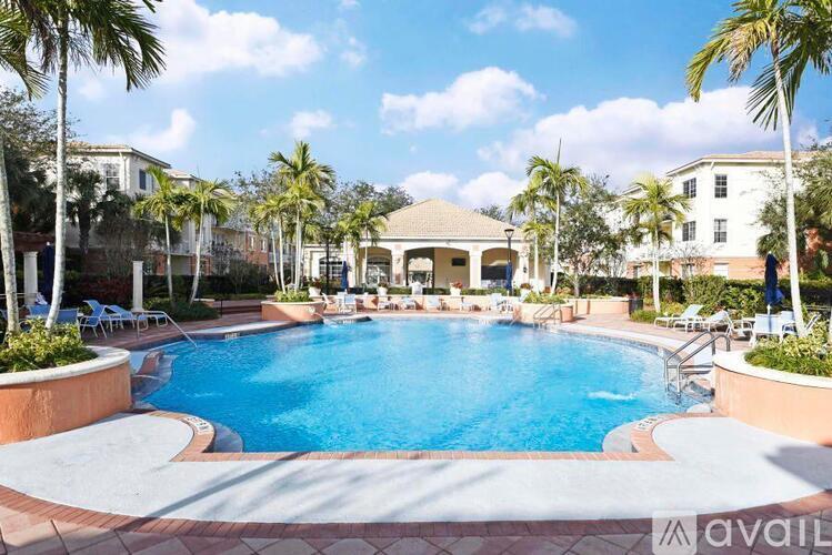A large swimming pool surrounded by palm trees and lounge chairs.