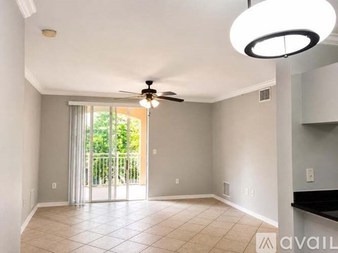 A spacious room with a ceiling fan and sliding glass doors leading to a balcony.