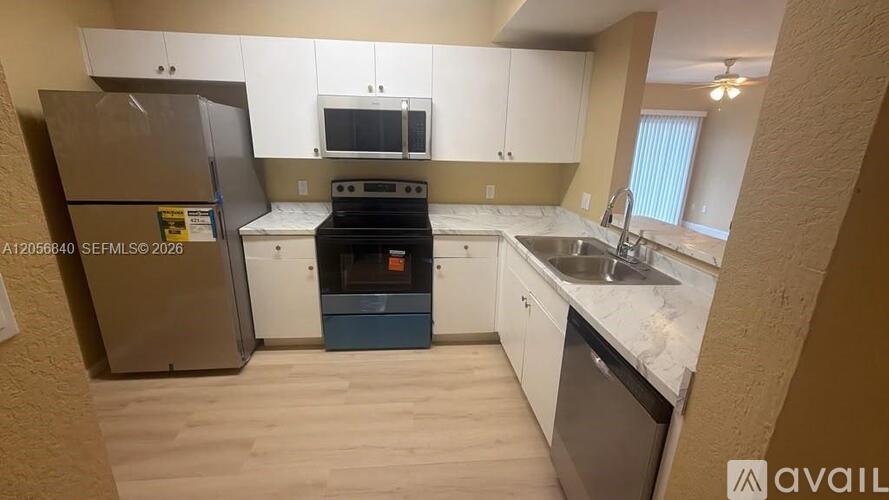 A kitchen with white cabinets and a stainless steel refrigerator.