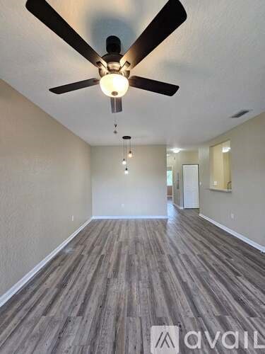 A room with a ceiling fan and wooden flooring.