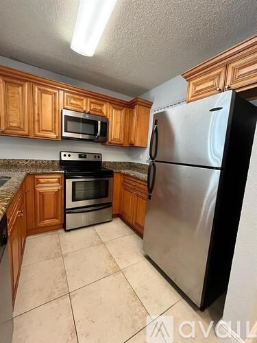 A kitchen with wooden cabinets and a stainless steel refrigerator.