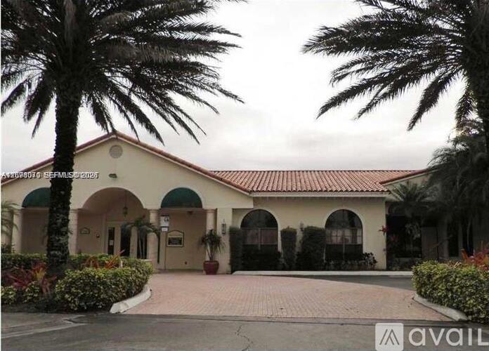 A building with a red roof and palm trees in front.