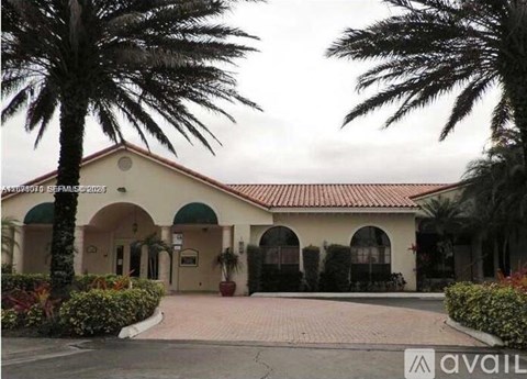 A building with a red roof and palm trees in front.