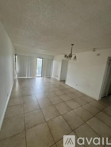 A spacious room with tiled flooring and a ceiling fan.