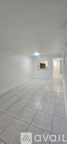 A spacious room with white walls and tiled flooring.