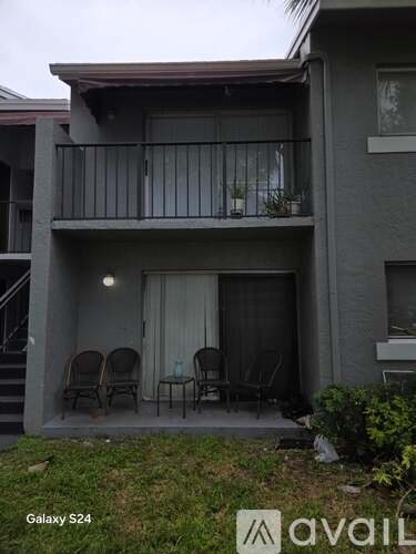 A grey two-story building with a balcony and patio furniture.