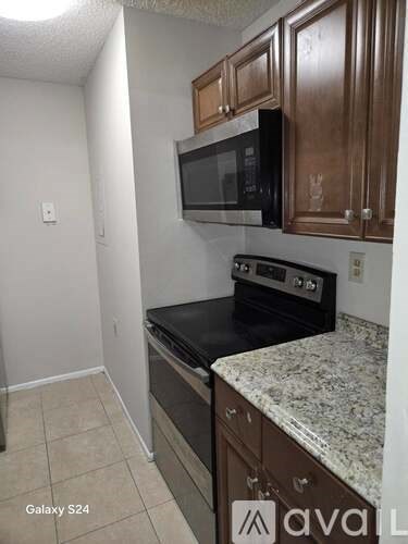 A kitchen with a black counter top and brown cabinets.
