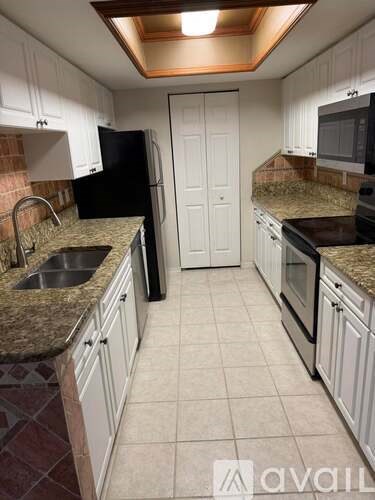 A kitchen with granite countertops and white cabinets.