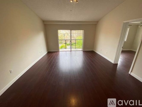 A spacious room with wooden floors and a large window.