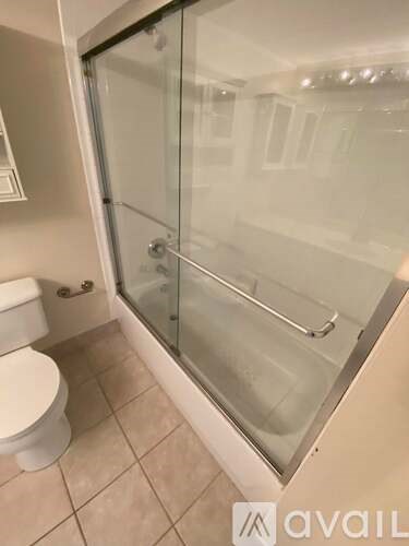 A bathroom with a toilet, a glass shower door, and a tiled floor.