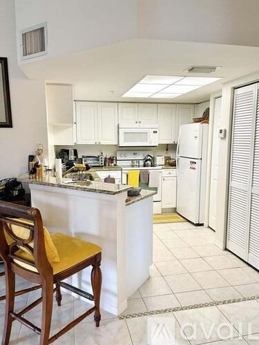 A kitchen with a white fridge and a yellow chair.