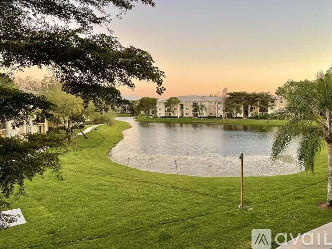A serene landscape with a lake, trees, and a building in the distance.