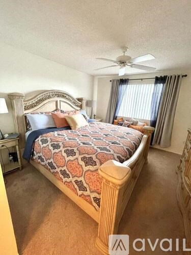 A bedroom with a large bed and a ceiling fan.