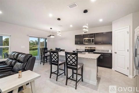 A modern kitchen with black cabinets and a white island.