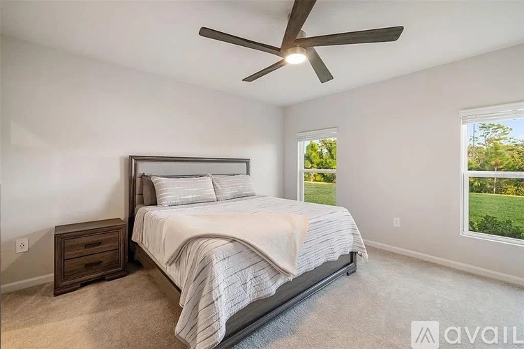 A bedroom with a large bed and a ceiling fan.