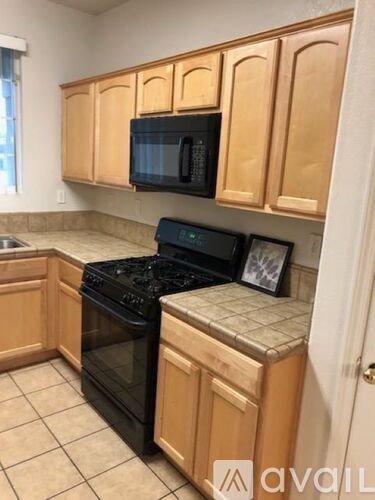 A kitchen with wooden cabinets and black appliances.