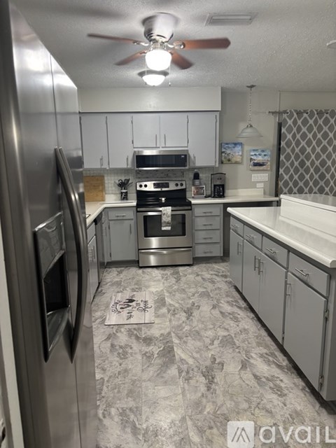 A kitchen with a refrigerator on the left and a stove top oven in the middle.