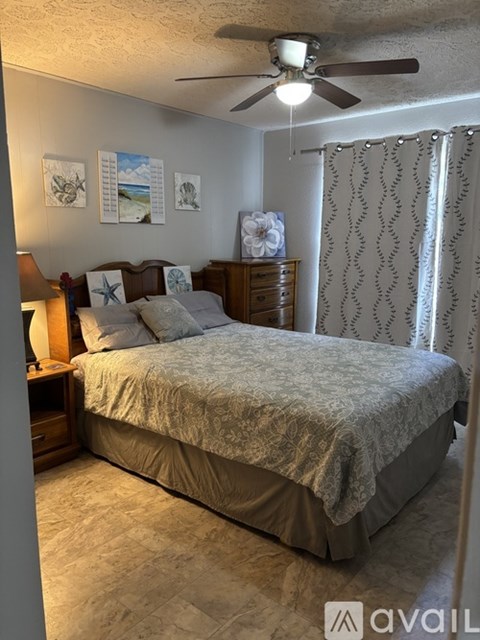 A bedroom with a bed, nightstand, and pictures on the wall.