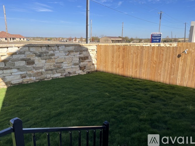 A backyard with a wooden fence and a stone wall.