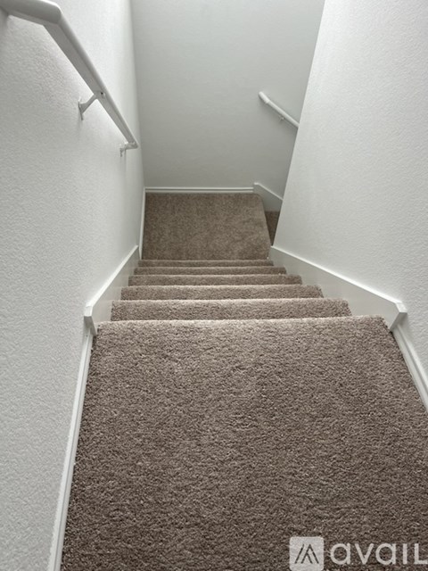 A staircase with a carpeted runner and white handrails.