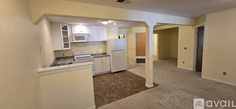 A kitchen area with a refrigerator, sink, and cabinets.