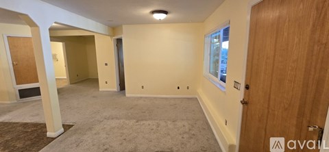 A spacious room with a carpeted floor and a window.