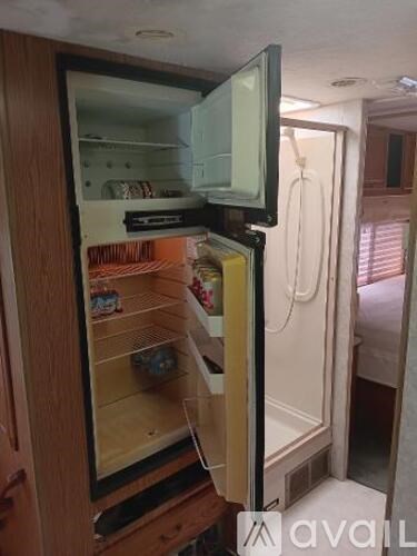 A small refrigerator with a TV on top is open.