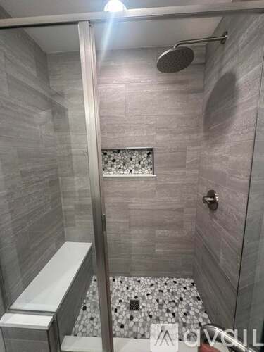 A shower area with a glass door and a shower head.
