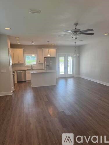 A spacious room with wooden flooring and a ceiling fan.