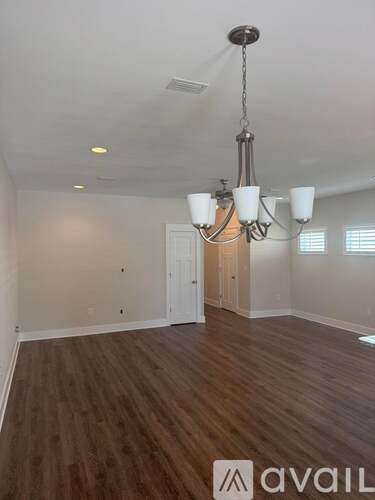 A room with wooden floors and a chandelier hanging from the ceiling.