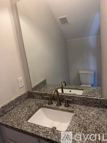 A bathroom with a granite countertop and a white sink.