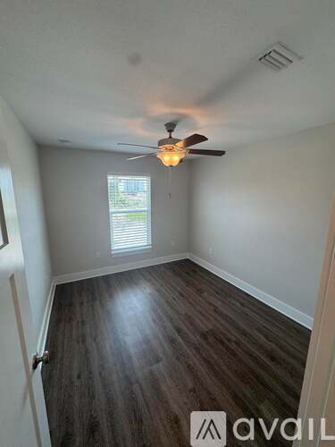 A room with a ceiling fan and wooden flooring.