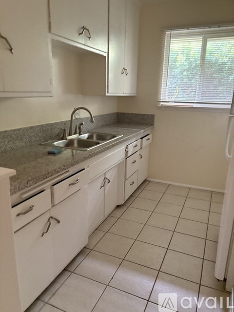 A kitchen with white cabinets and a granite countertop.