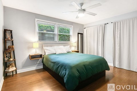 A bedroom with a bed, a fan, and a window with blinds.