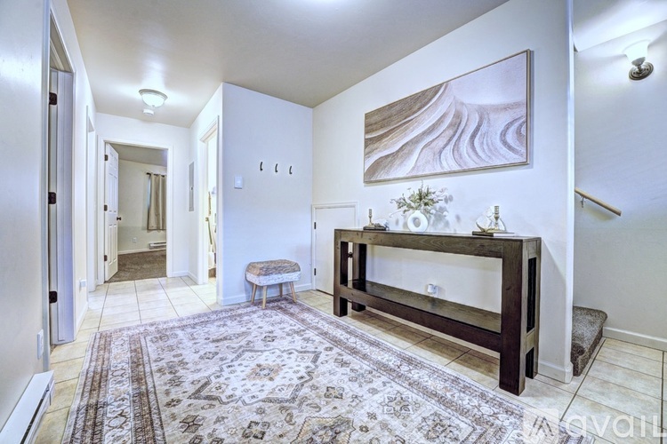 A living room with a rug, a bench, and a painting on the wall.