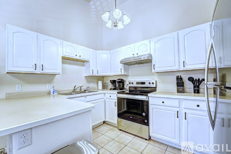 A white kitchen with a stainless steel sink and oven.