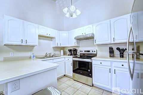 A white kitchen with a stainless steel sink and oven.