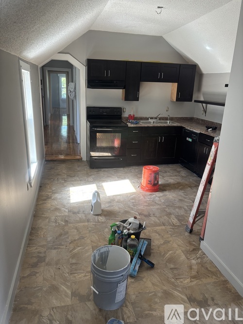 A kitchen with black cabinets and a wooden floor is under renovation.
