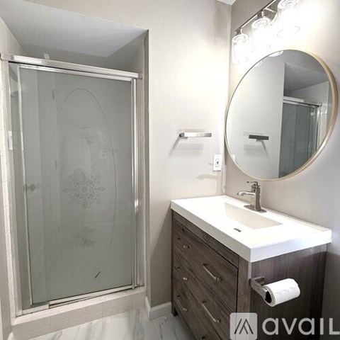 A bathroom with a sink, mirror, and shower.