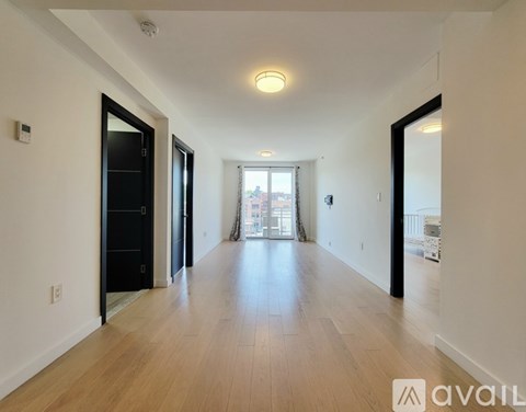 A long hallway with a door on the left and a window on the right.