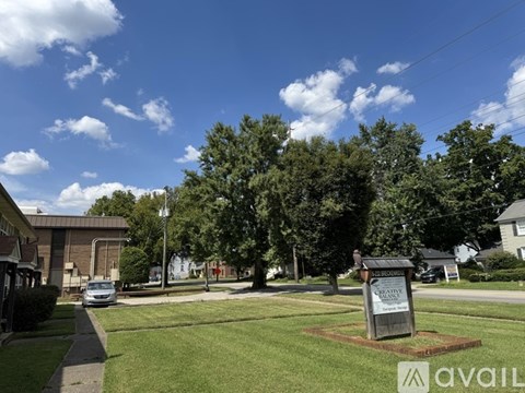 A sign in front of a grassy area with a building in the background.