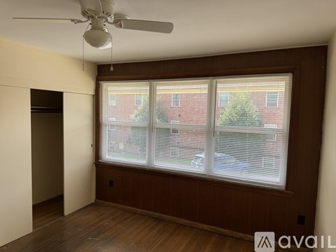 A room with a ceiling fan and a window overlooking a street.